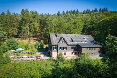 Ein charmantes Gebäude umgeben von Bäumen. Neben dem Haus gibt es eine Terrasse mit Sitzgelegenheiten im Freien.
