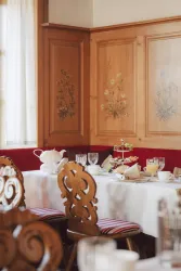 Ein einladender Essbereich mit dekorierten Holzwänden. Der Tisch ist festlich gedeckt mit Geschirr und frischen Speisen.