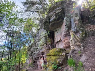 Eine beeindruckende Felsformation mit moosbedeckten Steinen und umgebenden Bäumen. Der Ort strahlt eine ruhige, natürliche Atmosphäre aus.