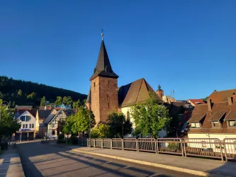 Eine schöne Stadtansicht mit einer Kirche und traditionellen Häusern. Der Himmel ist klar und blau, umgeben von Bäumen.