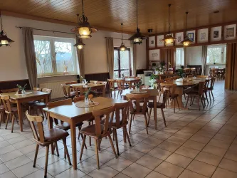 Ein gemütliches Restaurant mit vielen Holztischen und Stühlen. Die Fenster lassen viel Tageslicht herein und sorgen für eine einladende Atmosphäre.