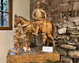 Eine Holzskulptur von St. Martin, der auf einem Pferd sitzt. Neben ihm kniet ein Bettler und bittet um Hilfe.