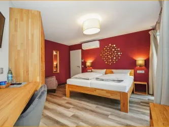 Ein modernes Schlafzimmer mit einem komfortablen Doppelbett und einem farbigen Wanddesign. Die helle Einrichtung schafft eine einladende Atmosphäre.