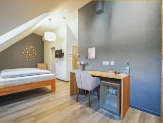 Ein modernes Zimmer mit einem Doppelbett und einer gemütlichen Sitzecke. Der Raum ist hell und freundlich mit Holzfußboden und stilvollen Dekorationselementen.