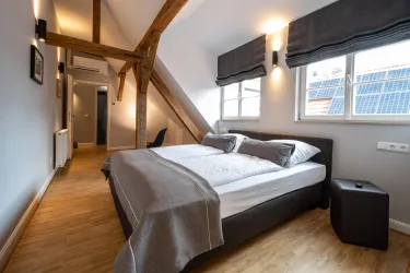 Ein modernes Schlafzimmer mit einem großen Bett und Holzmerkmalen. Große Fenster lassen viel Licht herein und bieten einen Blick auf die Außenseite.