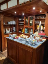 Eine gemütliche Bar aus Holz mit einer Auswahl an Getränken und Snacks. Auf dem Tisch stehen Früchte, Gebäck und verschiedene Gläser.