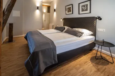 Ein modernes Schlafzimmer mit einem großen Doppelbett und hellen Wänden. Es gibt eine gemütliche Atmosphäre mit stimmungsvollem Licht.