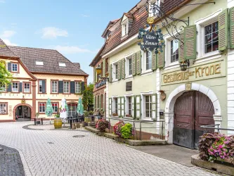 Eine charmante Altstadtstraße mit traditionellen Gebäuden und blühenden Pflanzen. Die Atmosphäre ist einladend und freundlich.
