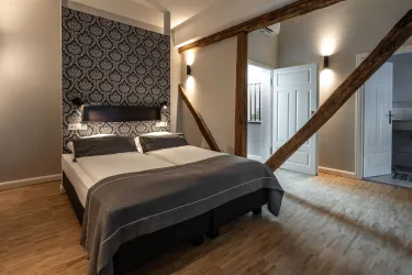 Ein stilvolles Schlafzimmer mit einem großen Bett und modernen Möbeln. Die Wände haben ein elegantes Muster und Holzstrukturen schaffen eine gemütliche Atmosphäre.