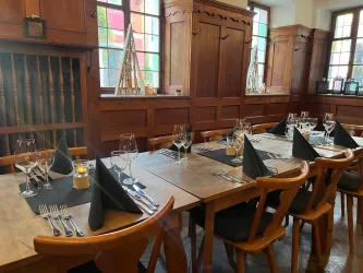 Ein stilvolles Restaurant mit Holzmöbeln und elegant gedeckten Tischen. Die Tische sind mit Gläsern, Servietten und Besteck für ein Abendessen vorbereitet.