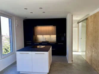 Eine moderne Küche mit einer hellen Farbgebung und einem zentralen Kücheninseln. Große Fenster sorgen für viel Tageslicht und einen offenen Raumgefühl.