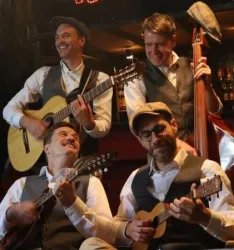 Eine Band spielt Musik auf verschiedenen Instrumenten. Die Musiker tragen klassische Anzüge und haben viel Spaß beim Auftritt.