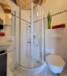 Eine moderne Duschkabine mit Glaswänden in einem Badezimmer. Neben der Dusche steht eine toilet und dekorative Handtücher.