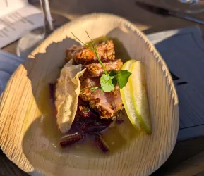 Ein köstliches Gericht auf einem Holztablett, bestehend aus frittiertem Fleisch, Beilagen und einer Scheibe Limette. Die Anordnung wirkt ansprechend und frisch.