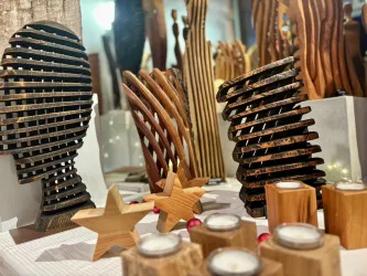 Eine Auswahl von kunstvollen Holzskulpturen in verschiedenen Formen und Farben. Dazu stehen dekorative Kerzenhalter und Sterne aus Holz.