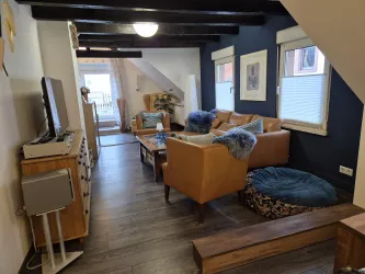 Ein gemütlicher Wohnraum mit einer modernen Einrichtung. Das Zimmer hat ein helles, freundliches Ambiente und einen schönen Blick nach draußen.