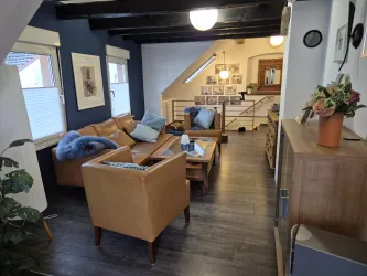 Ein gemütlicher Wohnbereich mit braunen Ledermöbeln und einer modernen Holzdecke. Der Raum ist hell und freundlich gestaltet, mit Pflanzen und Dekorationen.