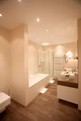Ein modernes Badezimmer mit einer Badewanne und einer separaten Dusche. Helle Wandfarben und Holzfußboden sorgen für eine gemütliche Atmosphäre.