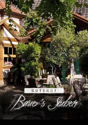 Ein einladender Gutshof mit einer gemütlichen Terrasse und viel Grün. Die Atmosphäre ist freundlich und einladend.