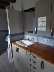 Ein modernes Bad mit einem Waschbecken und Holzdetails. Der Raum hat helle Wände und einen minimalistischen Stil.