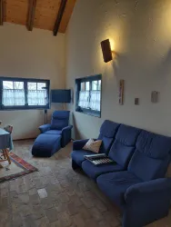 Ein gemütlicher Wohnraum mit blauen Sesseln und einem Sofa. Große Fenster lassen viel Tageslicht herein und verleihen dem Raum eine freundliche Atmosphäre.