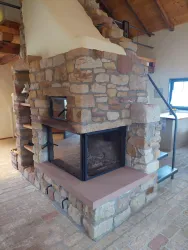 Ein rustikaler Kamin aus Stein in einem modernen Raum. Der Kamin hat eine klare Glasfront und fügt sich harmonisch in die Umgebung ein.