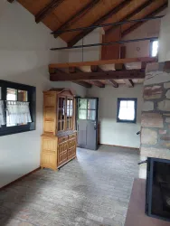 Ein gemütlicher Wohnraum mit Holzdecken und Steinwänden. Im Raum steht eine Holzmöbelstücke und es gibt eine offene Galerie.