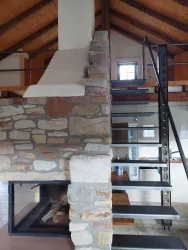 Eine moderne Treppe aus Stahl und Holz in einem offenen Wohnraum. Die Wand aus Naturstein ergänzt das ansprechende Innenarchitektur-Design.