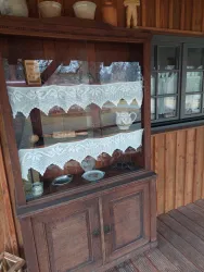 Ein rustikales Holzregal mit verzierten Stoffstreifen. Darin sind verschiedene dekorative Gegenstände und Geschirr ausgestellt.