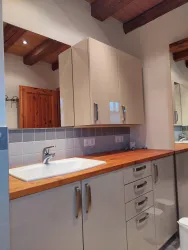 Ein modernes Badezimmer mit einem Holzwaschtisch und hellen Schränken. Die Holzdecke und die geflieste Wand verleihen einen warmen Touch.