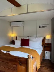Ein gemütliches Schlafzimmer mit einem großen Bett und weißen Kissen. Die Wände sind hell und es gibt zwei Nachttischlampen.