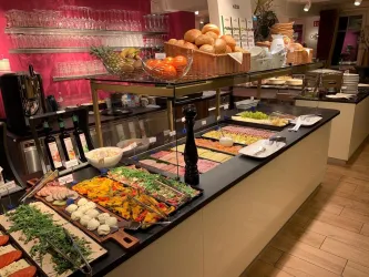 Ein Buffet mit verschiedenen frischen Speisen, darunter Gemüse, Aufschnitt und Brot. Die Anrichte ist ordentlich und einladend mit bunten Zutaten.