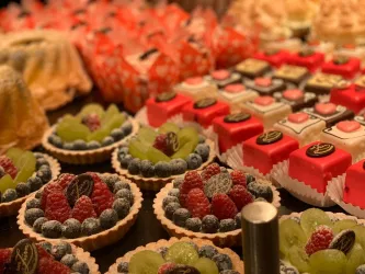 Eine Auswahl an bunten Desserts und kleinen Torten mit frischen Früchten. Die Leckereien sind ansprechend angerichtet und laden zum Probieren ein.
