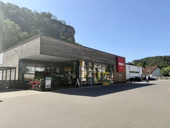 Ein moderner Supermarkt mit dem Namen "Penny" in einem städtischen Gebiet. Das Gebäude hat große Fenster und einen roten Eingang.