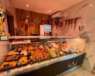 Ein eleganter Fleischereibereich mit einer Vielzahl von frischen Fleischwaren und Wurstprodukten. Die Vitrine ist gut beleuchtet und ansprechend präsentiert.