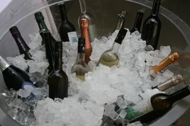 Eine Vielzahl von Wein- und Sektflaschen liegt in einem Eisbad. Die Flaschen sind teilweise mit Eiswürfeln bedeckt.