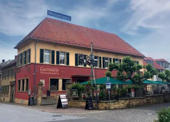 Gebäude der Winzergaststätte mit roter Fassade und Bestuhlung im Außenbereich