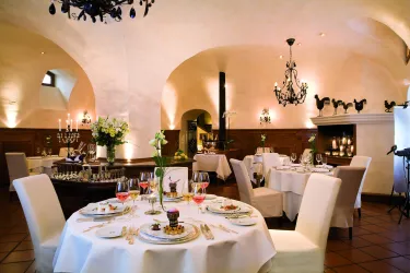 Ein elegantes Restaurant mit stilvollen Tischen und Tafeldekoration. Die warmen Farben und die beleuchteten Kronleuchter schaffen eine gemütliche Atmosphäre.