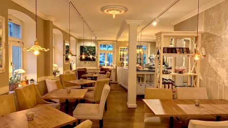 Ein modernes Restaurant mit warmem Licht und gemütlichen Holzmöbeln. Die Wände sind hell und dekoriert, während die Atmosphäre einladend wirkt.