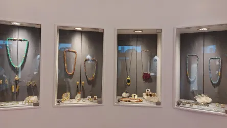 Eine Schmuckausstellung mit mehreren Vitrinen. Jede Vitrine zeigt verschiedene Halsketten und Schmuckstücke aus Edelsteinen und Metallen.
