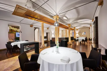 Ein elegantes Restaurant mit modernen Möbeln und stilvollen Säulen. Der Raum ist hell und einladend, ideal für ein gehobenes Essen.