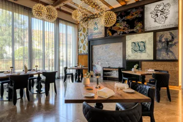 Ein stilvolles Restaurant mit modernen Tischen und eleganten Stühlen. Große Fenster sorgen für viel Tageslicht und einen einladenden Ambiente.