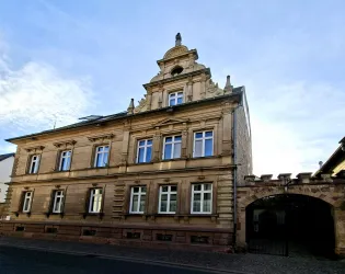 Ein historisches Gebäude mit einer eleganten Fassade und mehreren Fenstern. Der Himmel ist klar und trägt zur schönen Atmosphäre bei.