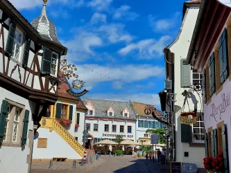 Eine malerische Straße mit traditionellen Fachwerkhäusern und hübschen Schildern. Im Hintergrund ist ein einladendes Restaurant sichtbar.