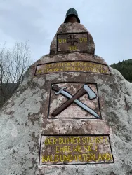 Der Ehrenfelsen erhebt sich als würdiger Gedenkstein, versehen mit Inschriften sowie Symbolen in Form von Kreuzen und Werkzeugen. Er erinnert an die gefallenen Soldaten und bewahrt ihr Andenken in ehrender Weise.
