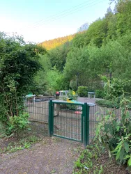 Eine Grünfläche mit einem Gartentor und dahinter mehrere Pit Pat Tische.