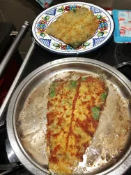 Zwei leckere, goldbraun gebratene Pfannkuchen auf einem Serviertablett, aus Wildkräutern.