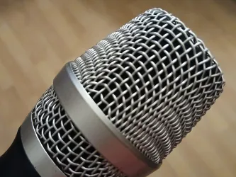 Ein nahes Bild eines Mikrofons mit einem metallenen Gitter. Die Oberfläche ist glänzend und detailliert.