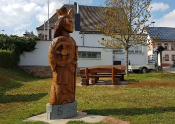 Zentrale Grünanlage mit Skulptur und Sitzgruppe