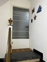 Ein Eingangstür zur Ferienwohnung Peter mit einer modernen Glastür. An der Wand hängen dekorative Sterne und ein Engel.